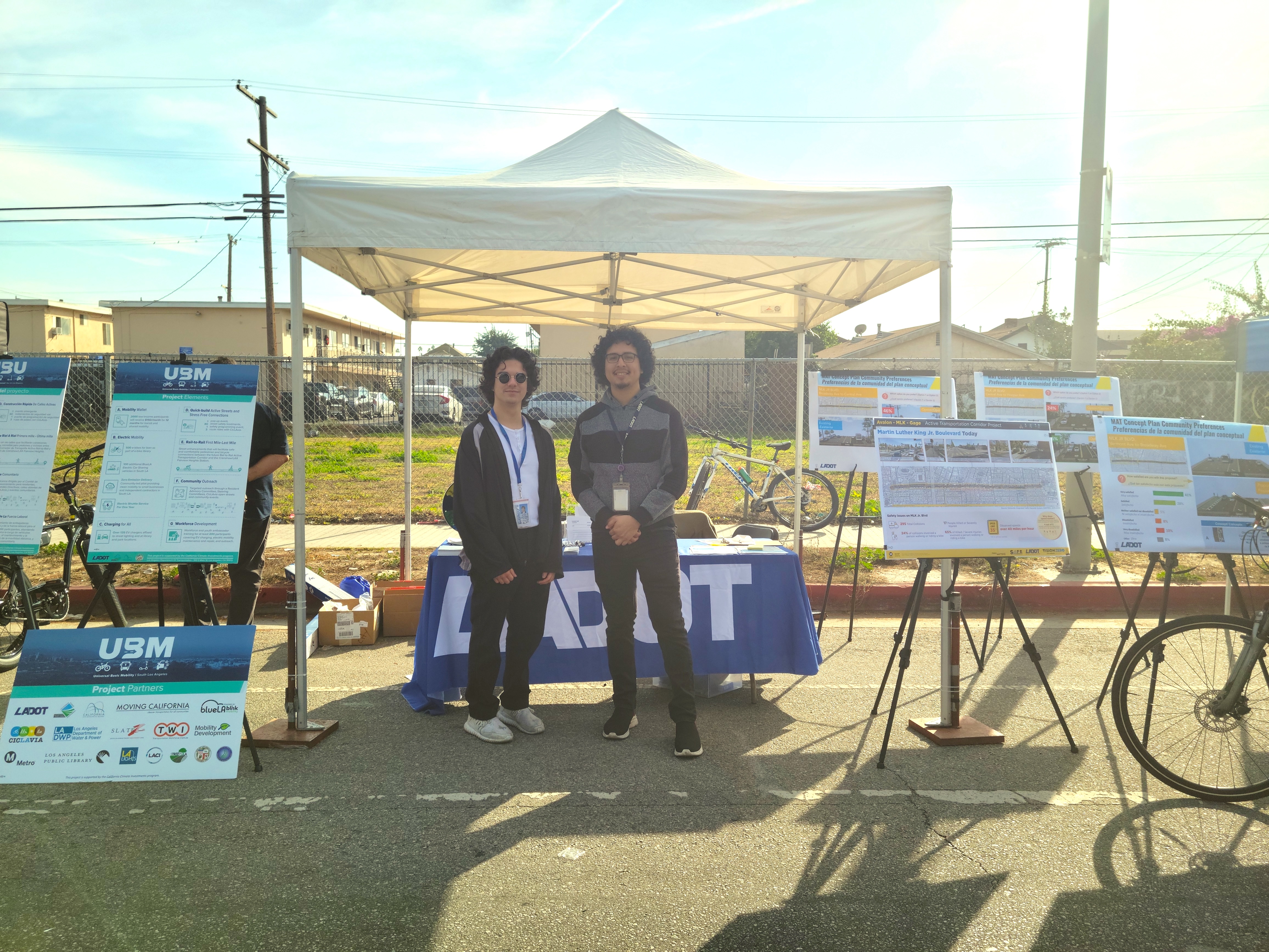 Two men stand in front of LADOT booth at CicLAvia with a bicycle and UBM branded signs