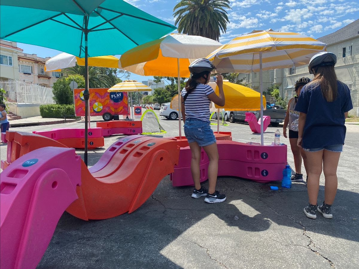 Kids playing with some Play Streets toys under beach umbrellas