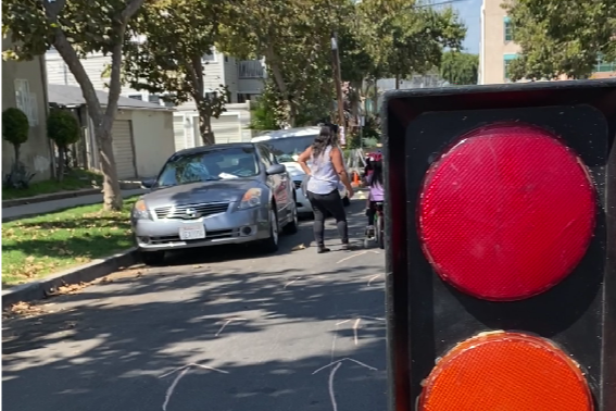 Zoom in on Play Streets model of traffic light with a kids riding a bike in the background